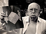 An old man holding a picture of a white box