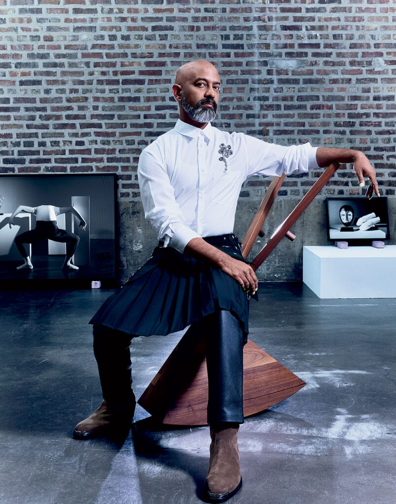 Brendan Fernandes wearing Givenchy wool and mohair pleated skirt, and Simone Rocha cotton shirt with crystal embellishment, Northbound custom leather jeans, and Jimmy Choo Sammy suede ankle boots.