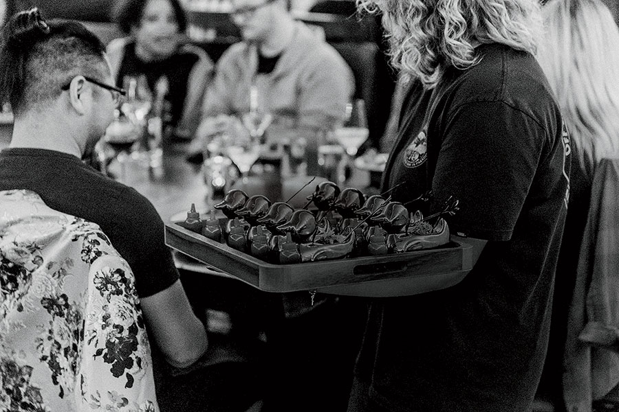 A server with a tray of food at a table filled with diners